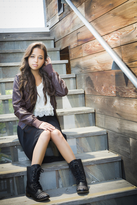 Portrait of a Pretty Mixed Race Young Adult Woman Sitting on a Staircase Wearing Leather Boots and Jacket.