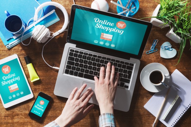 Online shopping website on laptop screen with female hands typing